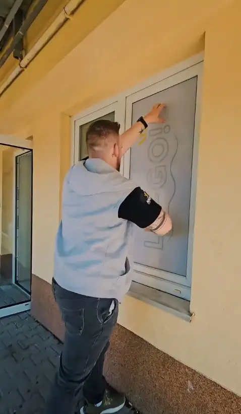 Adrian z Andale okleja folią szybę w gabinecie logopedycznym